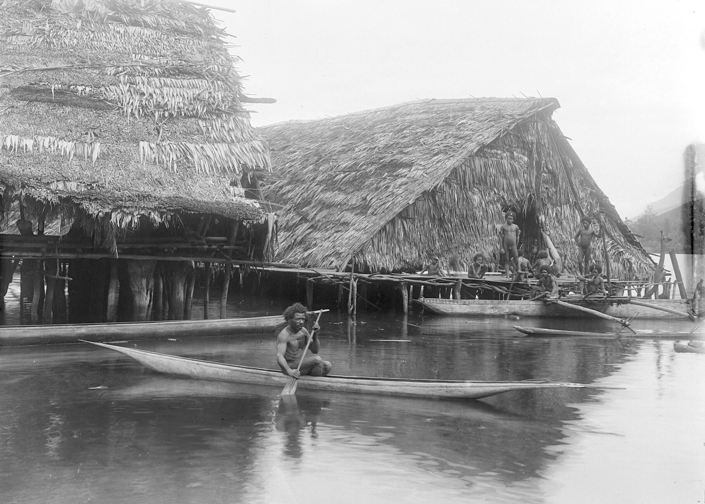 Papua man in een prauw bij paalwoningen op het eiland Asei in het Sentanimeer