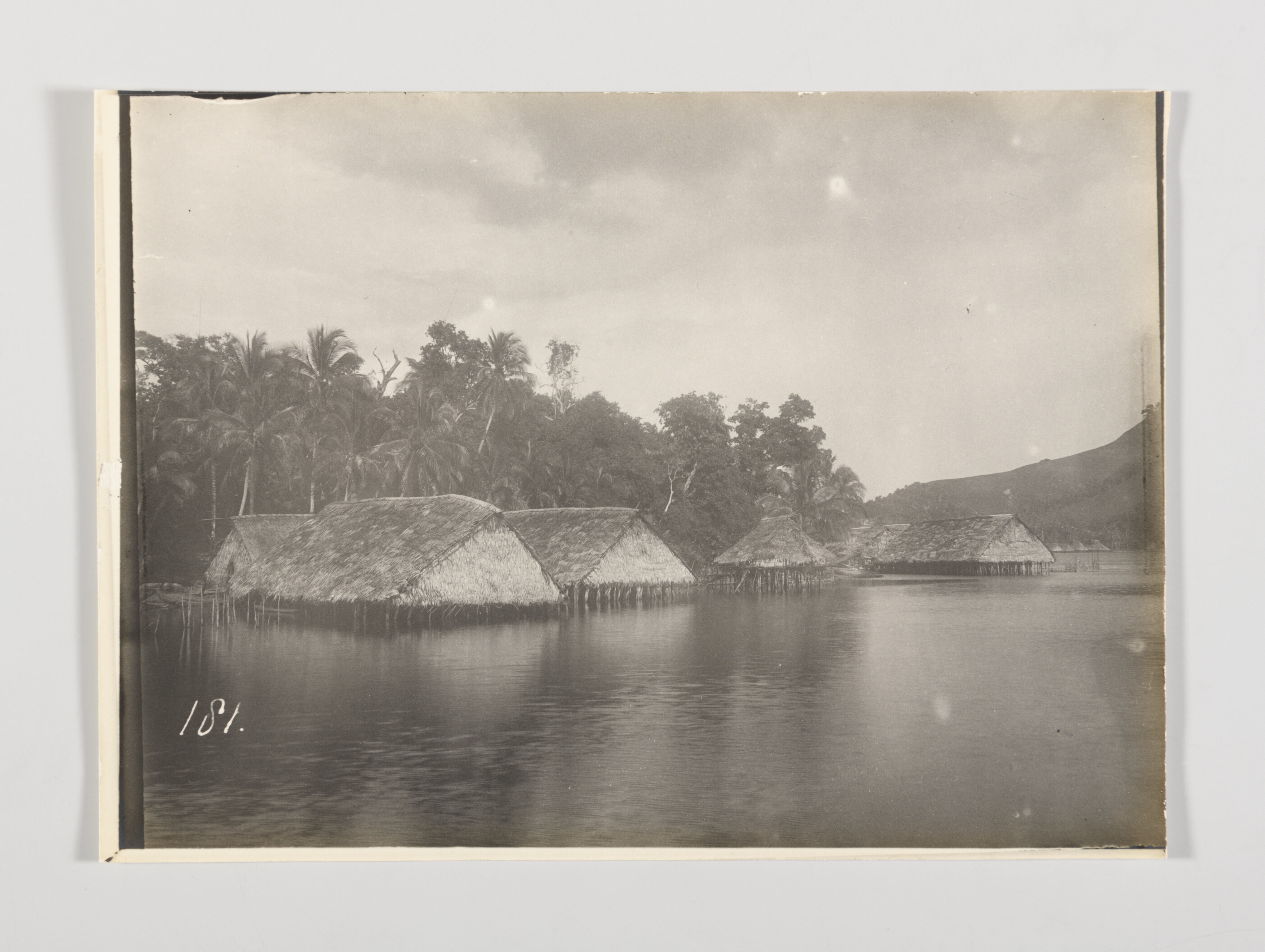 Dorpsgezicht met paalwoningen en een mannenhuis op Asé